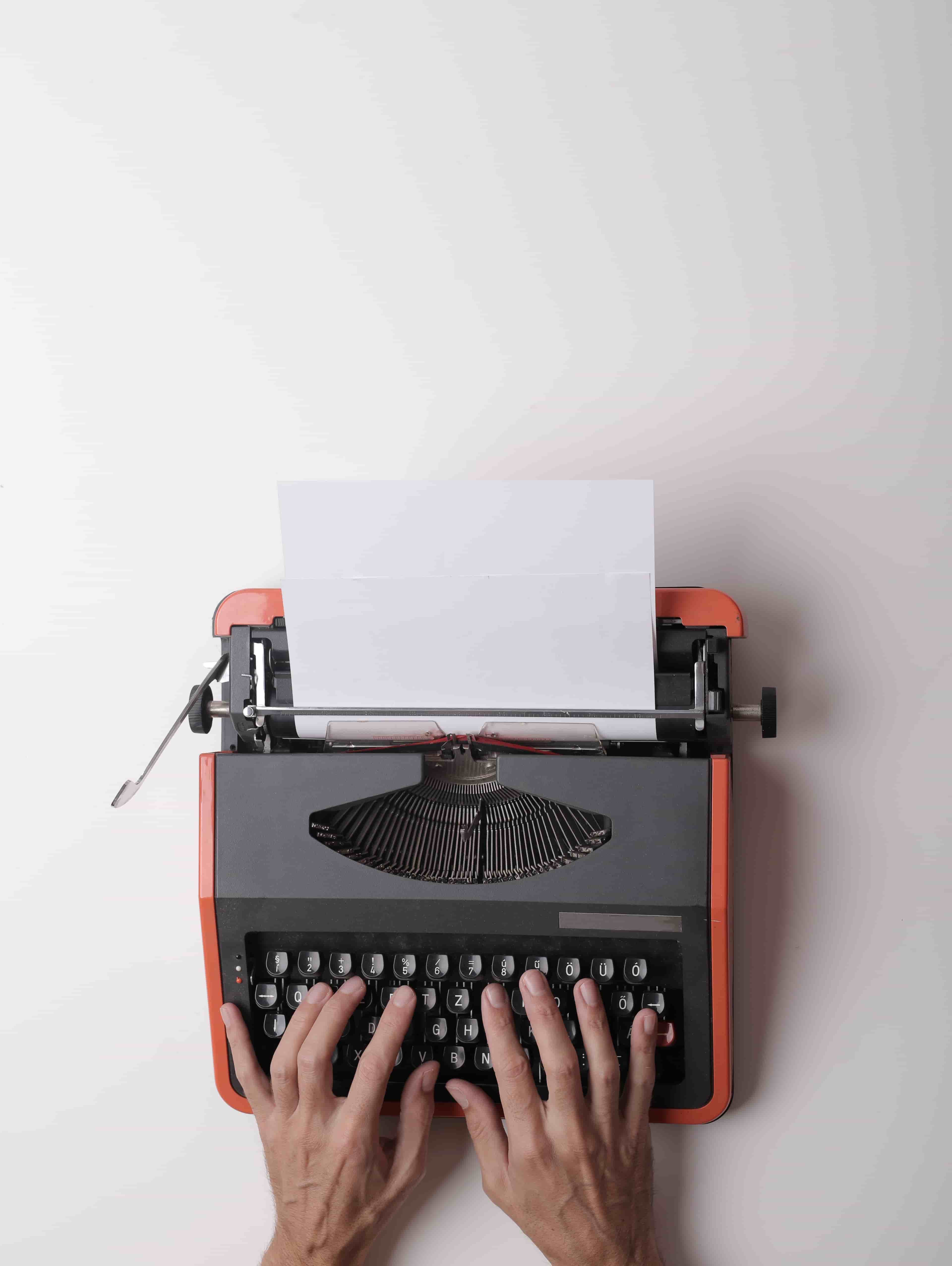 A typewriter with a blank sheet of paper, from above